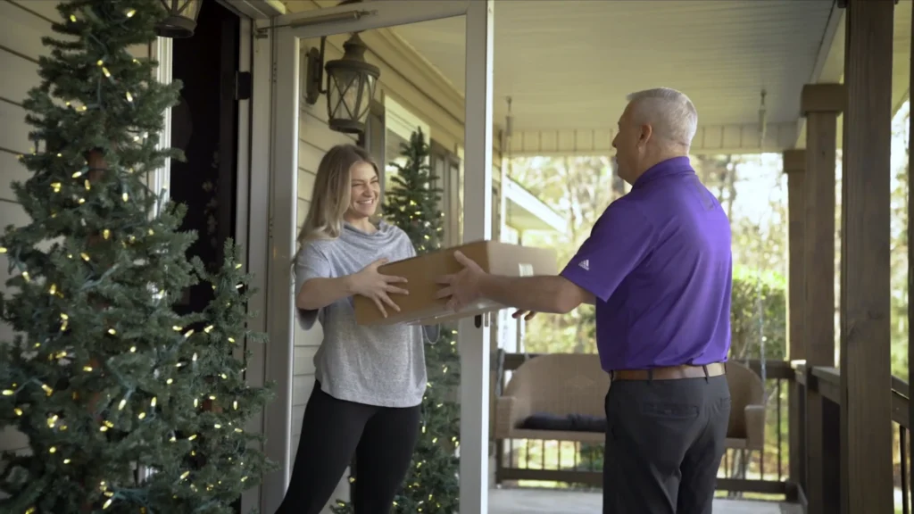 Delivery driver handing a package to a customer at her front door